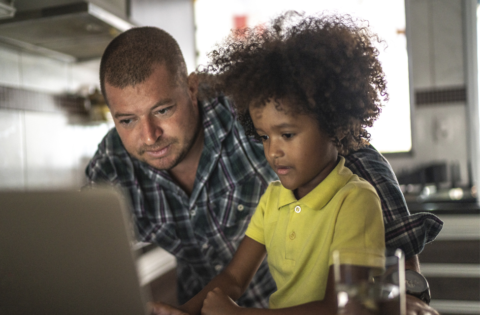 A father and his son work at a laptop.